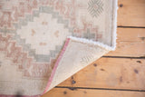 Hand-knotted foundation, worn pile texture, and intact pink selvage of the Oushak rug.