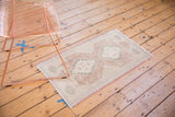 Angled view of a vintage distressed Oushak rug, showing secured side and muted geometric motifs.