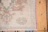 Vintage Oushak rug with faded burgundy side selvage and even worn ivory pile.