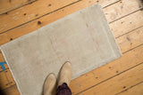 Secured edge of a vintage distressed Oushak rug, with soft beige and sand tones.