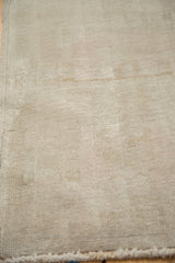 Distressed Oushak rug showing low pile texture and gentle beige, sand striations.