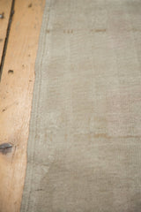 Muted beige low pile with abrashes and secured side of the vintage Oushak rug.