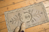Distressed vintage Oushak rug with central beige medallion, brown tendrils, and worn pile.