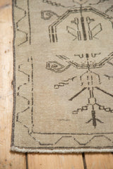 Worn beige pile of an Oushak rug with primitive dark brown plant motifs.