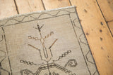 Vintage Oushak rug corner with meandering vine border, distressed beige pile, and secured edge.