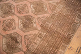 Distressed blush and brown geometric gul motifs meet multi-banded border on Afghan rug.