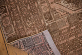 Distressed Afghan carpet corner, showing blush and brown gul motifs, low pile, and reverse foundation.