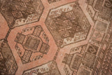 Repeating blush and coffee brown gul motifs with distressed low pile texture.