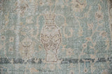 Distressed Sivas rug: faded pale green, antique ivory, with vase motif and foundation wear.