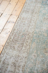 Worn pile texture of the distressed Sivas carpet with faded ocean green and beige tones.