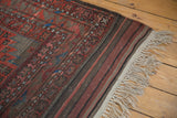Antique Persian Belouch carpet showing tribal geometric patterns, striped kilim, and antique ivory fringe.