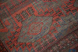Textured hand-knotted Belouch rug showing cherry red geometric guls and abrash.