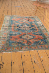Distressed vintage Veece rug's low pile texture, exposed knots, dusty teal, and brick red.