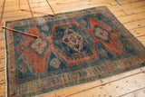 Distressed Veece rug border showing low pile, burnt orange, and dusty teal colors.