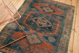 Distressed Veece rug, low pile texture, exposed knots, dusty teal, burnt orange, powder blue patterns.