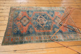 Distressed low pile and geometric border motifs in burnt orange and dusty teal.