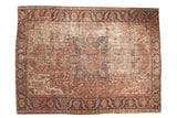 Vintage Heriz rug with oversized navy and cherry red medallion, intricate vinery, and aged ivory field, 7'11