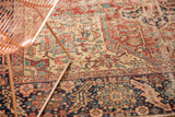 Localized wear on vintage Heriz carpet, revealing intricate red, ivory, and blue geometric vinery.