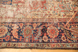 Heriz carpet's navy border with cherry red geometric patterns; worn field reveals foundation.