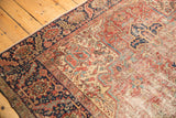 Worn cherry red pile with visible foundation on vintage Heriz rug's geometric patterns.