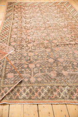 Distressed vintage Khotan carpet, faded blush pomegranates, worn dark brown pile, braided border.