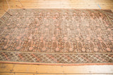 Distressed Khotan carpet showing dusty pink blooming pomegranate field and braided border.