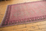 Distressed vintage Khotan runner with faded pink pomegranate motif and dark geometric borders.