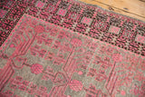 Vintage distressed Khotan runner detail: vibrant pink pomegranate field meets a dark geometric border.