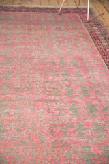 Distressed Khotan rug texture with pink pomegranate motifs, faint foundation visible.