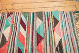 Colorful horizontal ribbon motif and triangle patterns on vintage Turkish rag rug.