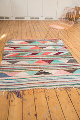 Vintage Turkish rag rug, showcasing playful striped pattern, colorful triangles, and hand-woven fringe.