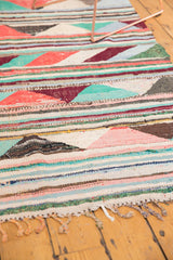 Colorful braided fringe and striped triangle patterns of a hand-woven vintage Turkish rag rug.