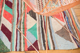 Textured view of vintage Turkish rag rug, featuring playful stripes and geometric triangles in vivid hues.