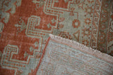 Distressed Veece carpet, faded brick red, seafoam geometric low pile revealing hand knotted foundation.