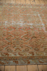 Distressed Malayer rug detail: faded blush rose, seafoam green herati motif, visible foundation.