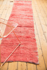 Faded cherry red Moroccan runner with abstract textural pile and visible shade variations.