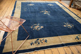 Vintage Peking carpet with dark indigo blue field and beige border, highlighting floral vinery and wear.