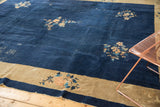 Ornate floral spray detail on vintage Peking carpet with indigo field and textured patina.