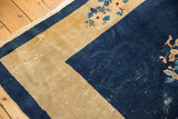 Corner detail of a vintage Peking rug: dark indigo field, beige border, delicate floral vinery, and visible wear.