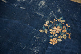 Vintage Peking carpet corner detail: beige and teal floral spray, dark indigo field, visible wear.