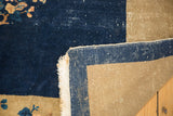 Vintage Peking carpet corner displaying dark indigo pile, white fringe, wear, and beige foundation.