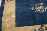 Vintage Peking carpet with dark indigo field, beige border, blush florals, and visible wear.