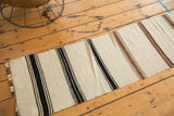 Vintage Turkish Kilim runner edge with frayed cut line, featuring ivory, black, and brown stripes.
