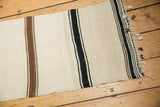 Vintage Turkish Kilim runner end with ivory, black, brown stripes, braided tassels, frayed edge.