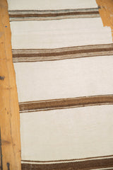 Vintage Turkish Kilim runner's ivory and coffee brown striped pattern, showing its frayed edge.