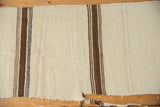 Frayed edge of the vintage Turkish Kilim runner with woven brown and black stripes.