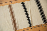 Frayed edge on the hand woven Turkish Kilim runner with ivory, brown, and black stripes.