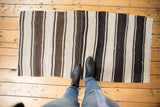 Hand woven Turkish Kilim rug with rhythmic vertical stripes in ivory and varying brown shades.