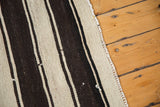 Textured edge of vintage Turkish Kilim rug, showing horizontal ivory and dark brown stripes.