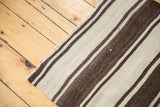 Textured hand woven vintage Turkish Kilim featuring ivory and brown stripes of varying widths.